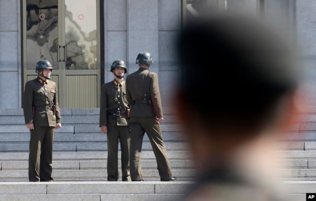 Tiga tentara Korea Utara berbindang, sementara tentara Korea Selatan (tengah) berdiri di desa perbatasan Panmunjom, Zona Demiliterisasi, Korea Selatan. (Foto: dok).