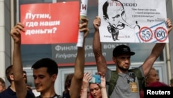 Protesters hold posters during a rally against planned increases to the nationwide pension age in St. Petersburg, Russia, Sept. 9, 2018. 