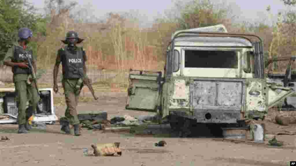 Police officers walk past the remains of a truck at a former Islamic extremist camp near Marte, Nigeria.