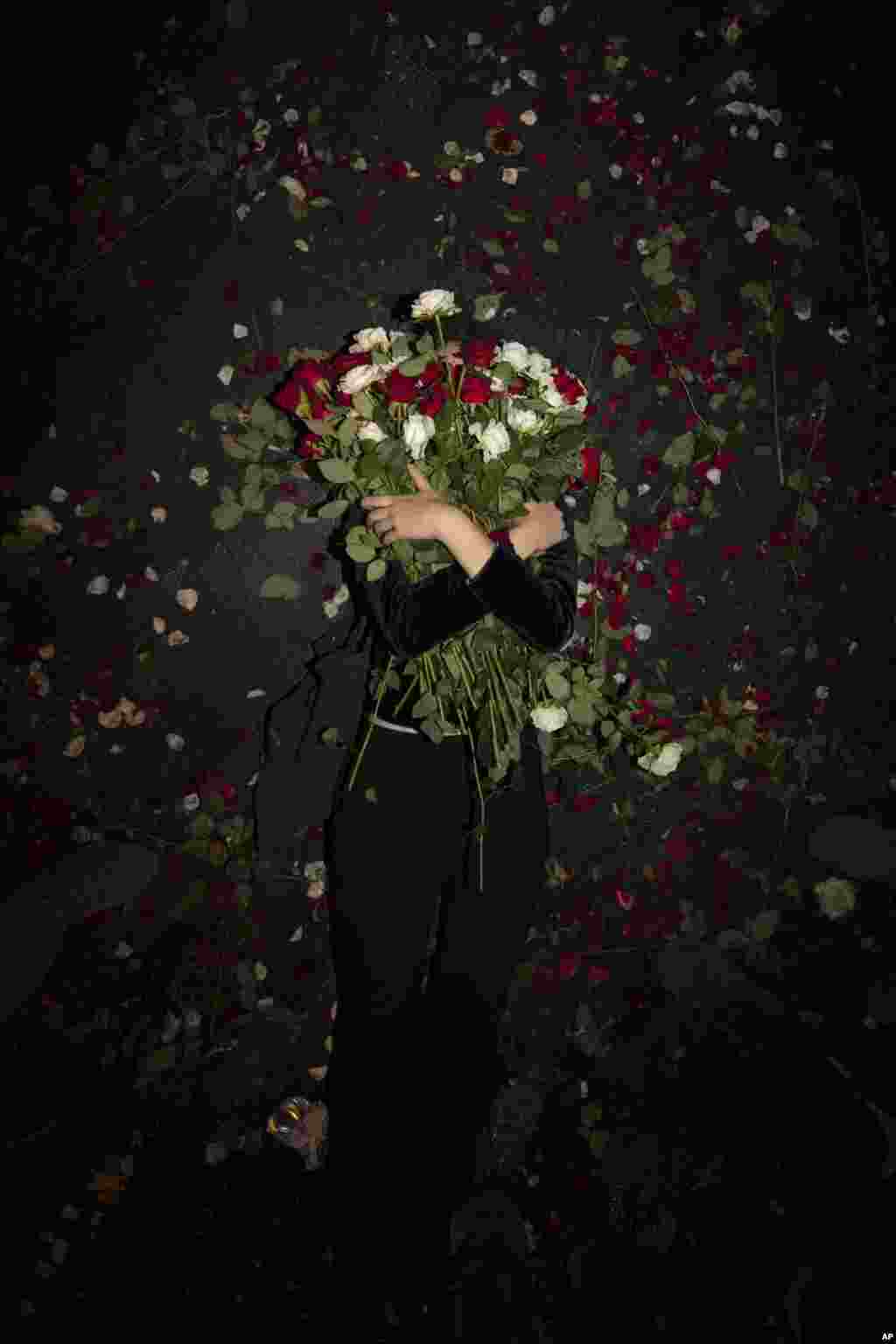 An Israeli protester holds flowers as she lies on the road during a demonstration against Prime Minister Benjamin Netanyahu near the Prime Minister&#39;s residence in Jerusalem, Aug. 15, 2020.