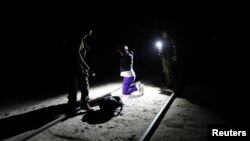 Migrant Yoniel Torres, 31, from Cuba is handcuffed after being detained by the police by a train line in a mined area of desert at the Chilean and Peruvian border in Arica, Chile, Nov. 14, 2018.