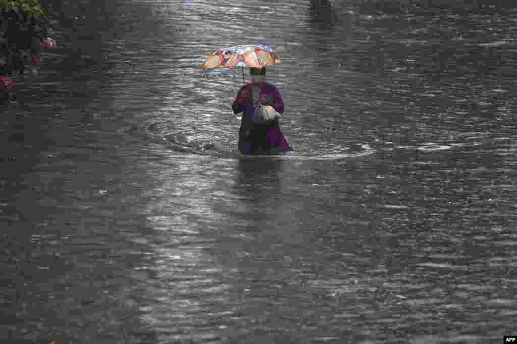 A woman walks through a flooded street after heavy rain showers in Mumbai, India.