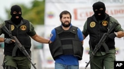 Daniel Barrera Barrera, one of Colombia's most wanted drug lords, whose alias is “El Loco” is escorted in a flak jacket by National Guard troopers as he is deported to Colombia from Venezuela, Nov. 14, 2012.