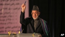 Presiden Afghanistan Hamid Karzai, memperlihatkan surat suaranya kepada media, sebelum memasukkannya ke dalam kotak di sebuah TPS di SMA Amani, dekat istana Presiden di Kabul, Afghanistan (5/4).