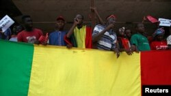 FILE - Supporters of Malian opposition talk as they stand behind the Malian flag during a protest against plans to revise the constitution, in Bamako, Mali, July 1, 2017.