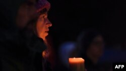A woman holds a candle during a vigil in Squirrel Hill, Oct. 27, 2018, to remember those that died in the Tree of Life Synagogue shooting earlier in the day. The gunman who killed 11 people at a synagogue in Pittsburgh will face federal charges that carry