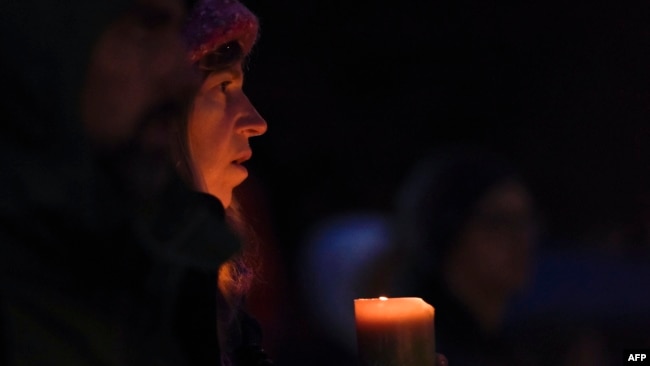 A woman holds a candle during a vigil in Squirrel Hill, Oct. 27, 2018, to remember those that died in the Tree of Life Synagogue shooting earlier in the day. The gunman who killed 11 people at a synagogue in Pittsburgh will face federal charges that carry