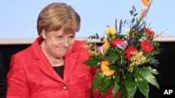 German Chancellor Angela Merkel holds a bouquet of flowers at a convention of the Christian Democrats’ branch in northeastern Mecklenburg-Western Pomerania state in Stralsund, Germany, Feb. 25, 2017.