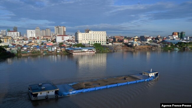 FILE - A cargo ship loaded with soil travels along the Tonle Sap river in Phnom Penh on Aug. 25, 2021.