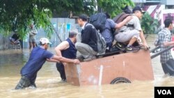 Masyarakat mengungsi dari banjir dengan menggunakan gerobak (13/1). (VOA/Iris Gera)