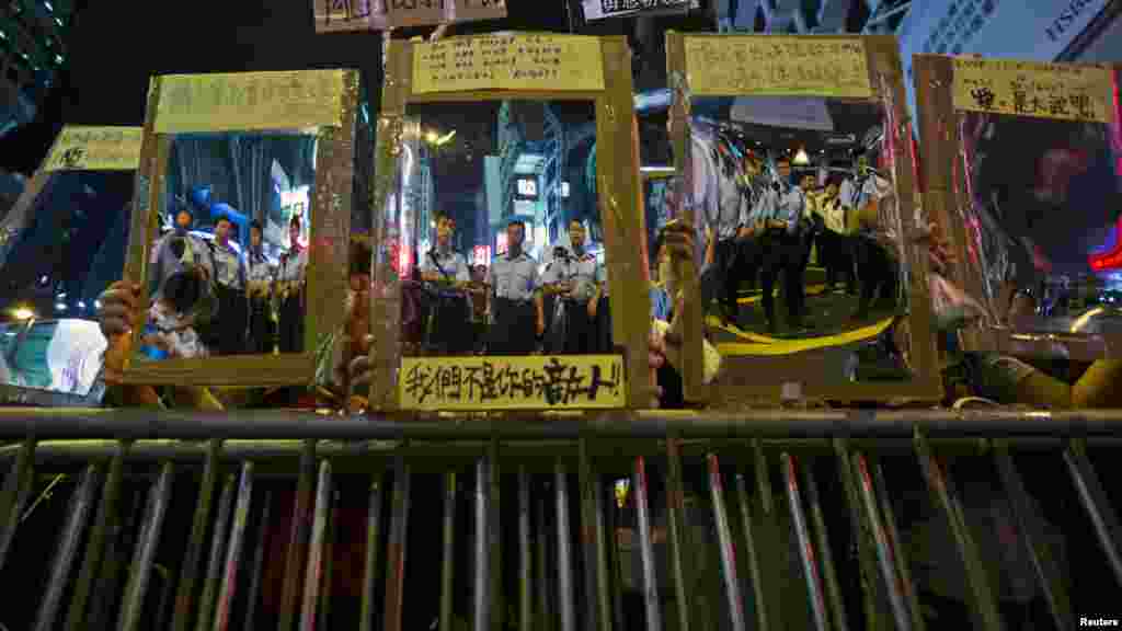 Police officers are reflected on reflective materials held by a pro-democracy protesters on a blocked road at Mongkok shopping district in Hong Kong, Oct. 19, 2014. 