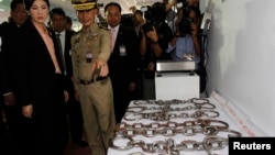 FILE - Thailand's Prime Minister Yingluck Shinawatra looks at chains on display at Bang Kwang Central Prison, May 15, 2013. Thailand announced that they will stop using manacles on inmates.