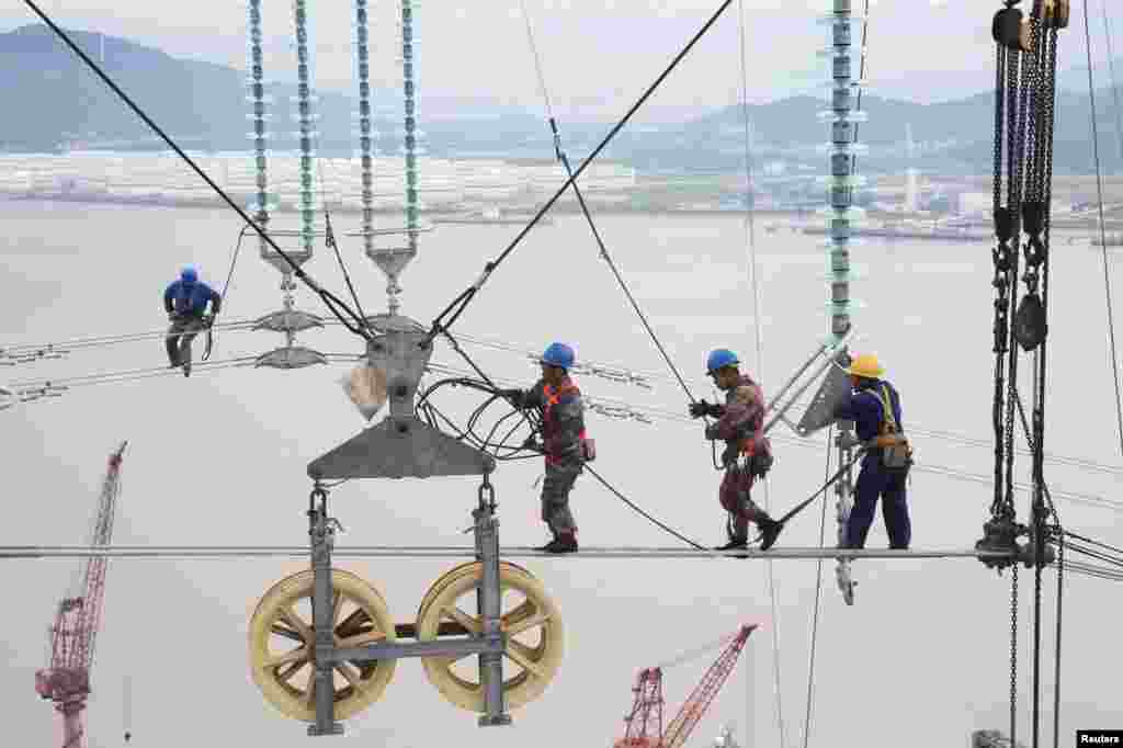 Men work on cables connecting power transmission towers in Zhoushan, Zhejiang province, China.