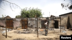 Un femme marche devant des maisons incendées lors d'une attaque de Boko Haram dans le village de Michika, dans l'Etat d'Adamawa, le 10 mai 2015. 