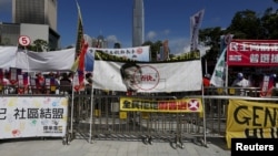 A banner featuring a portrait of Hong Kong Chief Executive Leung Chun-ying with a veto sign set up by pro-democracy protesters, is displayed in front of a pro-China rally outside Legislative Council in Hong Kong, China, June 18, 2015.