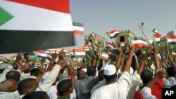 People wave Sudanese flags at soldiers during a celebration march outside Sudan's Defence Ministry in Khartoum, Sudan, April 20, 2012.