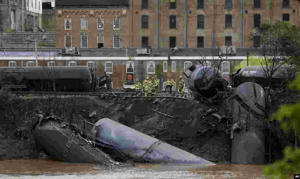 Firefighters and rescue workers work along the tracks where several CSX tanker cars carrying crude oil derailed and caught fire along the James River near downtown in Lynchburg, Virginia, USA, April 30, 2014.