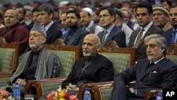 FILE - Afghan President Ashraf Ghani, center, former President Hamid Karzai, left, and Afghan chief executive Abdullah Abdullah, right, attend during a ceremony marking the first anniversary of the death of Former Afghan Vice President Marshal Mohammed Qa