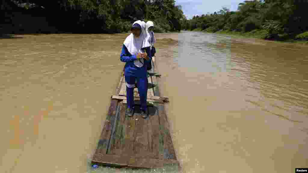 Para siswa puteri menyeberangi sungai Ciherang di Kabupaten Lebak, provinsi Banten, dengan rakit, karena jembatan yang rusak akibat banjir.