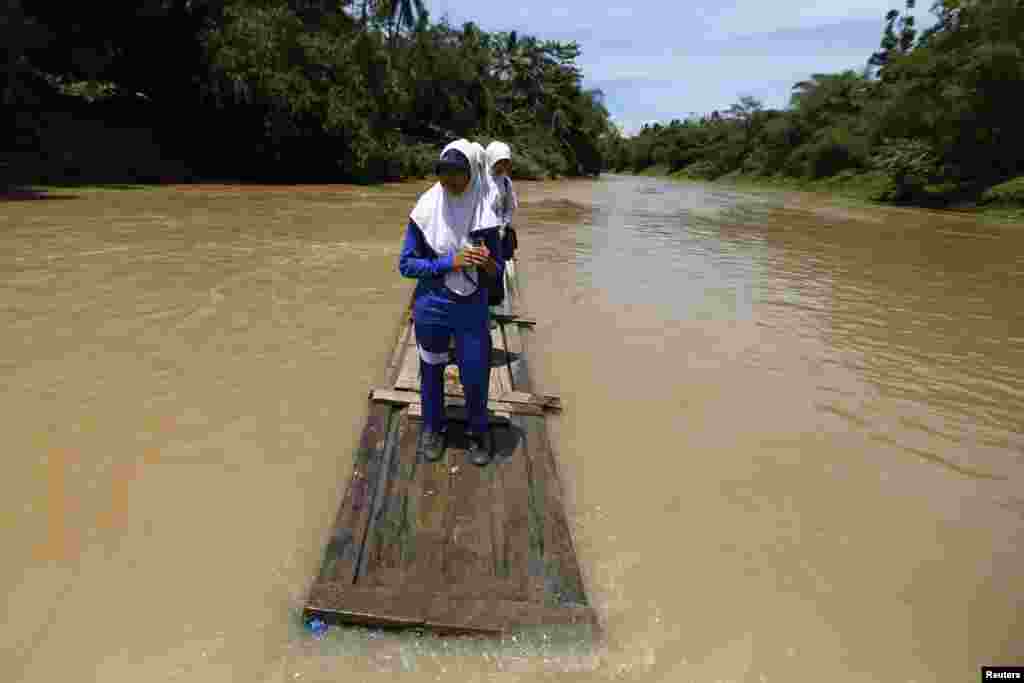 Students cross Ciherang river on a bamboo raft on their way home from school in Cilangkap village, Lebak Regency in Banten province, Indonesia. The raft has been used since January when the bridge collapsed due to flooding, local media reported.
