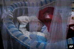 FILE - A newborn lies in her crib at the state-run al-Zuhour orphanage, in Mosul, Iraq, Aug. 19, 2018. Here, it's a mix of infants born to Iraqi women who were enslaved by militants and older children whose parents are jailed; some were simply abandoned in the chaos that follows a war.