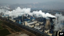 In this Nov. 28, 2019, photo, smoke and steam rise from a coal processing plant that produces carbon black, an ingredient in steel manufacturing, in Hejin in central China's Shanxi province. (AP Photo/Sam McNeil)