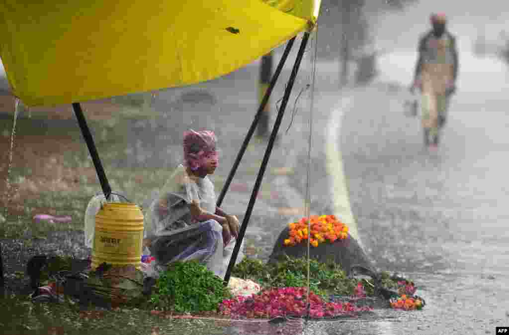 A boy waits for customers at a flower stall during heavy rain in Allahabad, India.