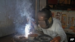 A man welds a wheel used for packing medicine inside a factory in the western Indian city of Ahmedabad. India's factory sector expanded at its slowest pace in more than two years in August as export orders shrank amid weakening global demand, September 2,