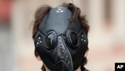 A man wears a mask as demonstrators gather to protest the COVID-19 preventative measures downtown Prague, Czech Republic. (AP Photo/Petr David Josek)