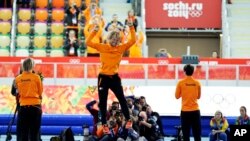 Gold medalist Michel Mulder from the Netherlands jumps in celebration, flanked by Silver medalist Jan Smeekens, right, and bronze medalist Ronald Mulder during the flower ceremony for the men's 500-meter speed skating race at the Adler Arena Skating Cente