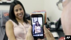 FILE - Lauren Simo (L) answers questions during a weekly forum streamed via Periscope on a smartphone, Hollywood, Fla., 29, 2015.