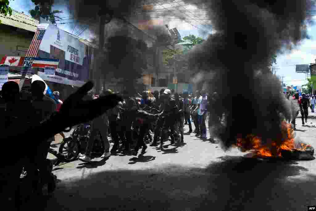 Demonstrators walk past burning tires during a protest march against the ruling government in Port-au-Prince, Haiti, on June 13, 2019.