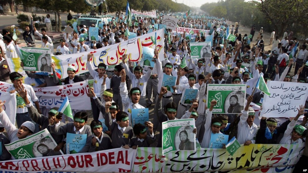 FILE - Students chant slogans while holding banners and posters showing Mumtaz Qadri, the alleged killer of Punjab governor Salman Taseer, during a rally to protest against any attempts to modify blasphemy laws, in Karachi, Pakistan, Jan. 20, 2011. Pakistani authorities on Feb. 29, 2016, hanged Qadri, a former police bodyguard.