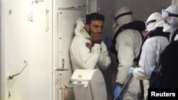 Un migrant rescapé du naufrage, à gauche, secouru par la le bateau des gardes-côtes italiens, Catane, Italie, lundi 20 avril 2015.