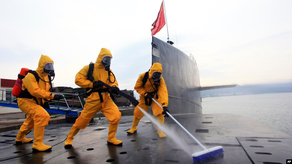 中国海军发布的照片显示，在青岛潜艇基地，穿着防护服的水兵清洁核潜艇 