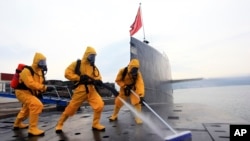 中国海军发布的照片显示，在青岛潜艇基地，穿着防护服的水兵清洁核潜艇。（2013年10月）