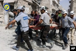 FILE - In this photo, provided by the Syrian Civil Defense White Helmets, rescue workers work the site of airstrikes in the al-Sakhour neighborhood of the rebel-held part of eastern Aleppo, Syria, Sept. 21, 2016. Violence in Aleppo has surged in recent da