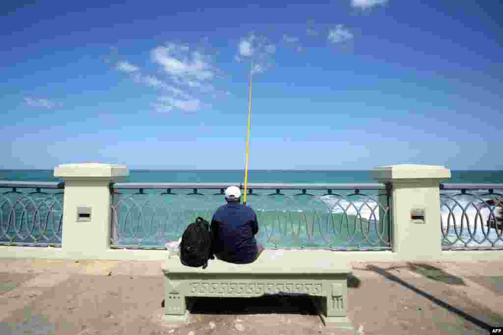 A man fishes while sitting on a bench on the Stanley Bridge in the Stanley neighborhood of the Egyptian port of Alexandria.