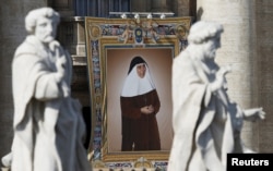 A tapestry showing Maria Isabel Salvat Romero hangs from a balcony as Pope Francis leads the mass for a canonization in Saint Peter's Square at the Vatican, Oct. 18, 2015.