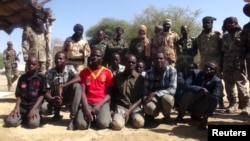 Des anciens membres du groupe Boko Haram devant des soldats tchadien à Ngouboua, Tchad, le 22 avril 2015.