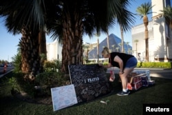 A woman writes a message on a sign at a makeshift memorial in the middle of Las Vegas Boulevard following the mass shooting in Las Vegas, Nevada, Oct. 5, 2017.