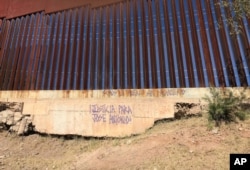 FILE - An inscription asking for justice for Jose Antonio Elena Rodriguez, 16, who was shot and killed on a street in Nogales, Sonora, Mexico, is displayed at the border wall where he was killed, Dec. 4, 2017.