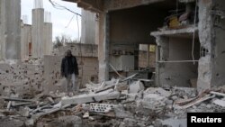 A man inspects a damaged house after an airstrike on al-Yadouda village, in Deraa Governorate, Syria, Feb. 15, 2017.