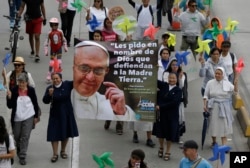 FILE - Nuns hold a banner with an image of Pope Francis and a message that reads in Spanish: "I ask you in the name of God to defend Mother Earth" during a silent march calling for action to tackle climate change, in Bogota, Colombia, Nov. 29, 2015.