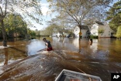 Ethan Abbott pulls his boat down Mayfield St. to help a friend get personal items out of the house in the Ashborough subdivision near Summerville, S.C., Oct. 6, 2015.