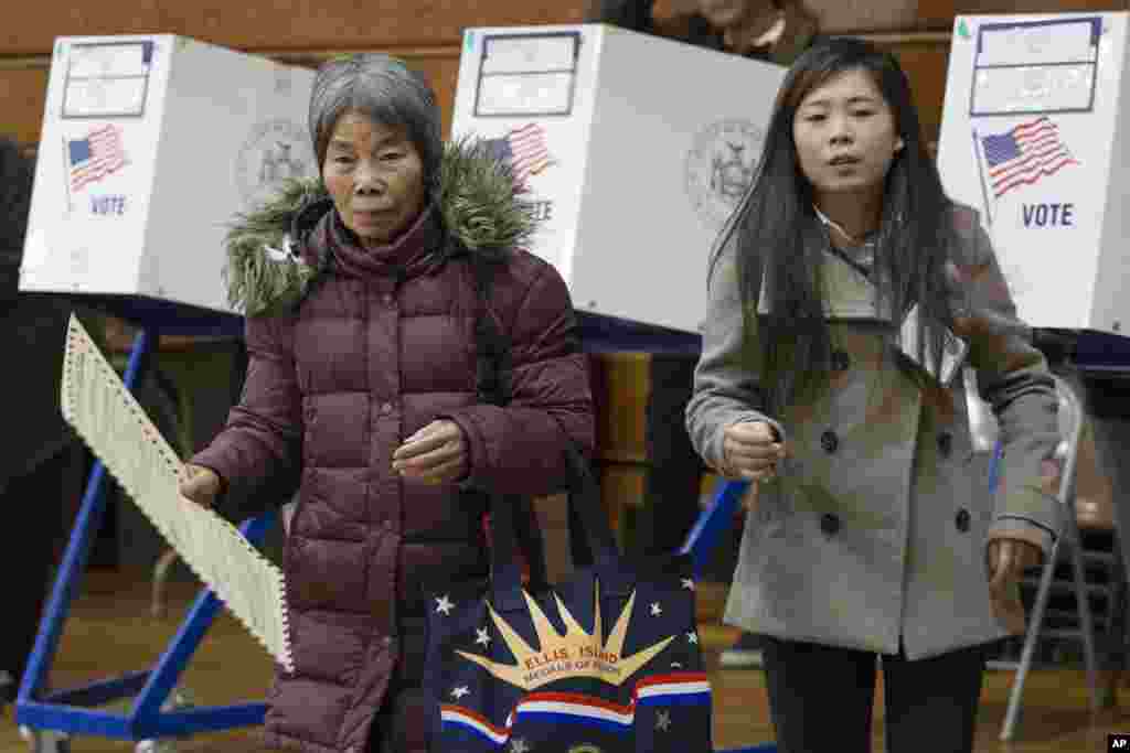 A voter, left, carries her ballot, while being assisted by interpreter Ping Chan, Nov. 8, 2016, in the Sunset Park neighborhood in the Brooklyn borough of New York. 