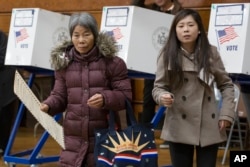 A voter, left, carries her ballot, while being assisted by interpreter Ping Chan, Nov. 8, 2016, in the Sunset Park neighborhood in the Brooklyn borough of New York.