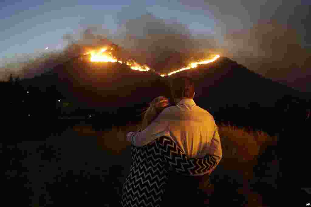 Roger Bloxberg, right, and his wife Anne hug as they watch a wildfire on a hill top near their home Nov. 9, 2018, in West Hills, Calif.