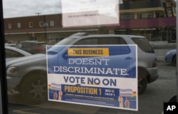 In this photo taken Monday, April 9, 2018, is a sign on a business door urging defeat of a proposition that would have rolled back protections for transgender residents in Anchorage, Alaska.