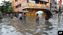 FILE - People wade through a flooded street in Chennai, in the southern Indian state of Tamil Nadu.